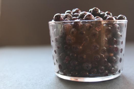 blueberries or blackcurrants on a gray black background with a place for text and copyspace view from the side.