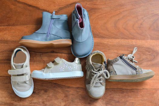 Different children's shoes on a wooden background