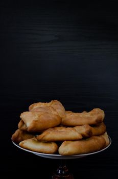 A plate with fresh pies on a black wooden table, Copy space