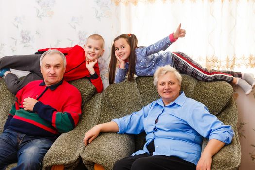 Grandparents and their young grandchildren relaxing at home