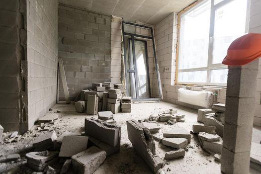 Break the wall for renovation and build the door for entrance of building. Wheelbarrow with broken bricks in site construction.