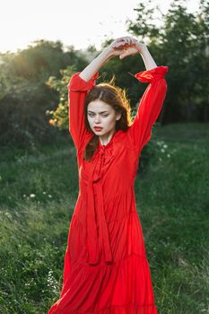 attractive woman in red dress posing in nature green grass. High quality photo