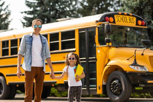 Girl with father going back to school near the school bus