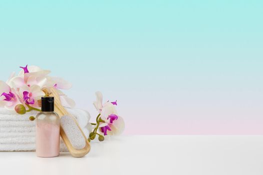 Stack of white towels and bottles of skincare on white table, front view