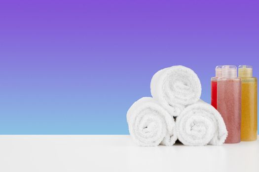 Pile of towels, bottles with shampoo on white table isolated