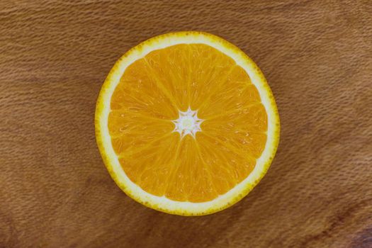 Single sliced valencia orange fruit (Citrus x sinensis) centered on wood surface