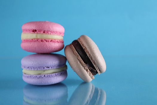 three macaroons lie triangle on a blue background with a place for text and copyspace.