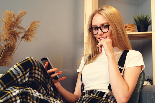 Young woman using mobile phone. Sitting on the couch. Stay home concept during coronavirus covid-2019. Close up.