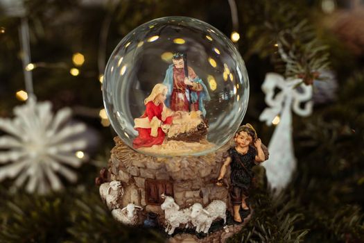 Scene of the nativity of Jesus Christ in a glass ball on a Christmas tree