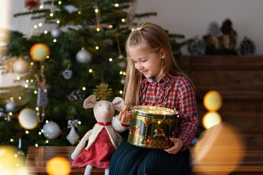 Girl with the presents sits near the Christmas tree