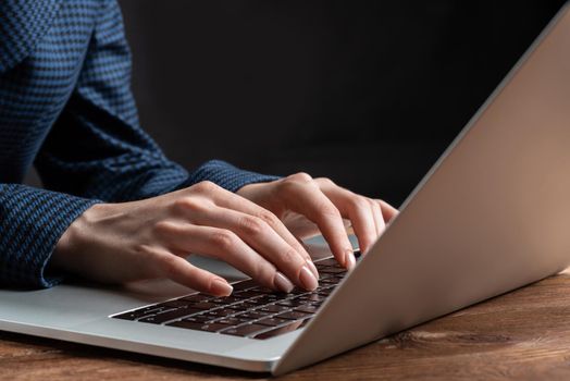 Close up woman hands lying on laptop keyboard. Business lady working with computer at wooden desk. Financial specialist working at workplace in office. Business accounting and project management.
