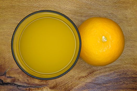 Valencia orange (Citrus x sinensis) citrus fruit with glass of juice top view layout on rough wood