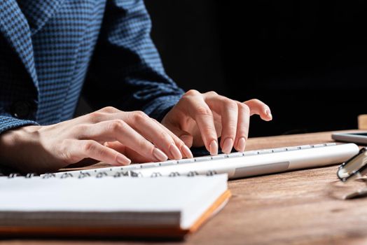Close up woman hands lying on laptop keyboard. Business lady working with computer at wooden desk. Financial specialist working at workplace in office. Business accounting and project management.