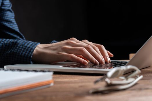 Close up woman hands lying on laptop keyboard. Business lady working with computer at wooden desk. Financial specialist working at workplace in office. Human resources and career development.