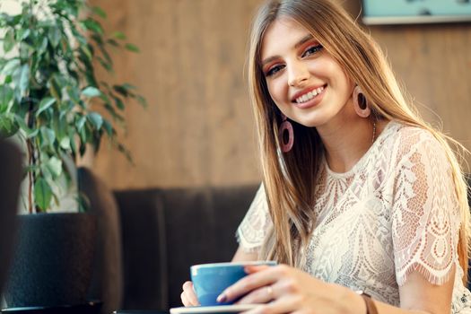 Nice young woman enjoying cup of coffee in a coffee shop. Close up.