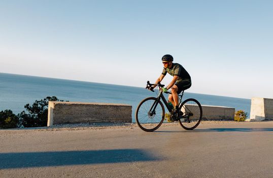 Cycling sport athlete man riding on coastal road at dawn