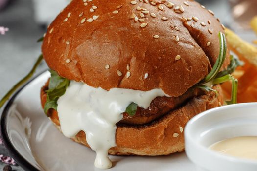 burger with fries and sauce on a white plate.