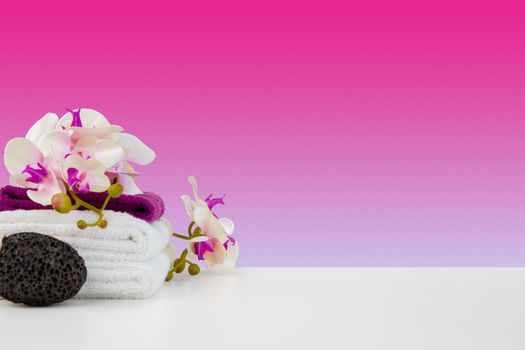 Beautiful pink flowers and white towels on pink background, front view