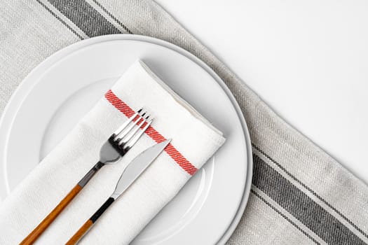 Fork, knife and plate on towel. Isolated on white background. Close up.