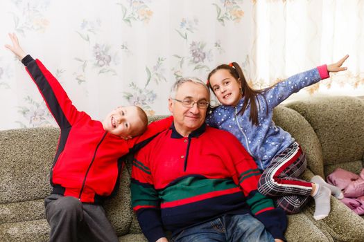 grandfather spends time with grandchildren in the living room