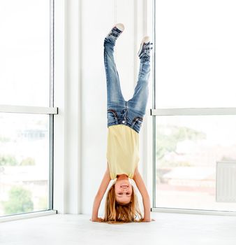 Young schoolgirl making training, doing hand stand indoors