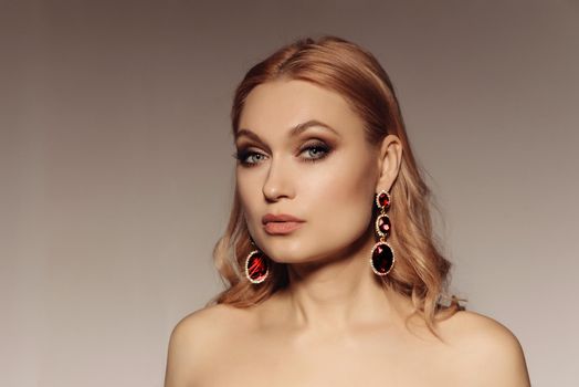 Elegant portrait of a middle-aged woman with big earrings with red stones. Gorgeous luxury statement accessory.
