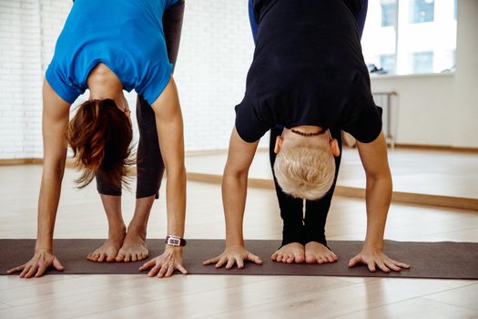 Women stand in an intense stretch pose on the rug