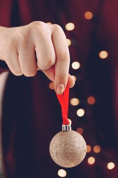Female hand holding a Christmas ball close up, festive background