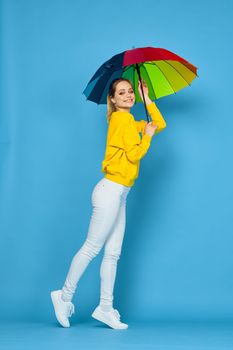 woman with multicolored umbrella in yellow sweater posing rainbow colors. High quality photo