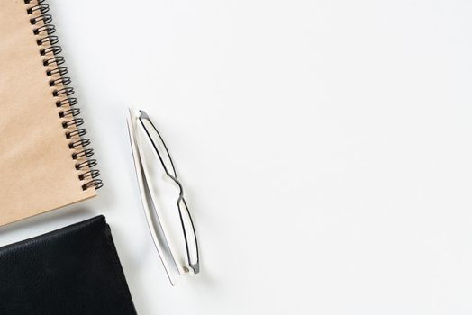 Still life of modern office workspace with supplies. Flat lay white desk with black leather wallet and spiral notepad. Accounting and banking service. Finance and investment concept with copy space