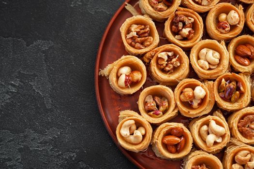 Delicious baklava dessert in oriental setting on black background, close up
