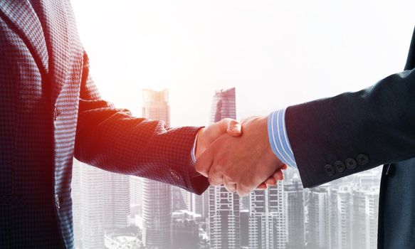 Close-up of the handshake of businessmen. Against the backdrop of the cityscape