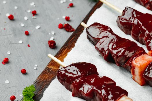 Raw liver kebab on skewers on wooden board close up