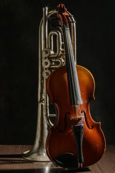 Old violin and trumpet on a black background.