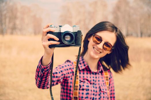 Happy woman takes photographs with old photo camera outdoor
