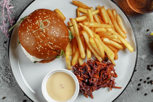 burger with fries and sauce on a white plate.