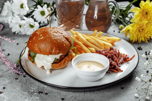 burger with fries and sauce on a white plate.