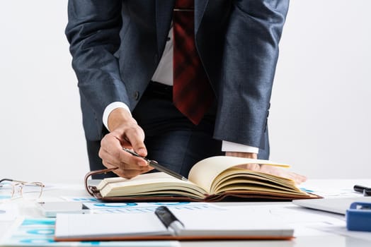 Businessman analyzing financial documents at office desk. Financial expertise and consulting. Manager in suit and tie planning day with personal organizer. Time management and work organization.