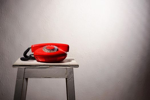 red vintage phone on a white stool. copyspase on background