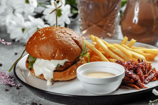 burger with fries and sauce on a white plate.