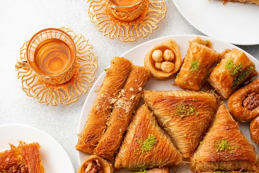 Various Turkish sweets and cup of tea on white textured background, close up