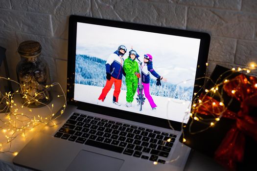 Image of open laptop family and christmas on wooden table in front of christmas tree background.