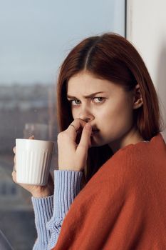 woman with hot near window in plaid rest at home. High quality photo