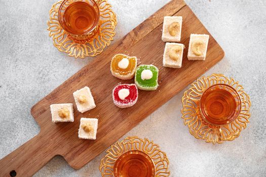 Various Turkish sweets and cup of tea on white textured background, close up