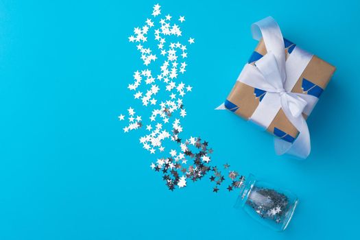 Wrapped Christmas gifts with confetti on blue background top view