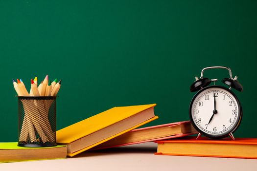 School supplies on wooden desk against green chalkboard front view