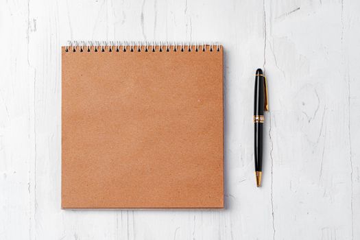 Top view of brown open notepad with pen on wooden table, copy space