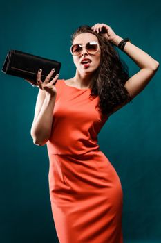Beautiful girl with a sunglasses and clutch bag in her hands