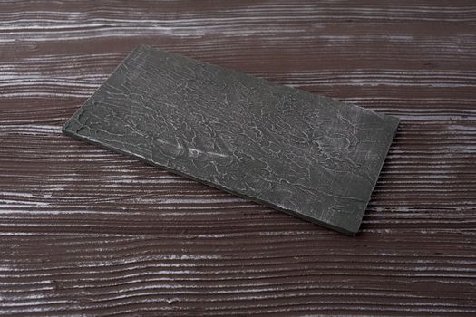 Rectangular piece of slate stone on a woden background - image