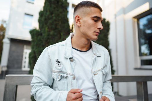 Young casual man sitting on stairs alone on city street